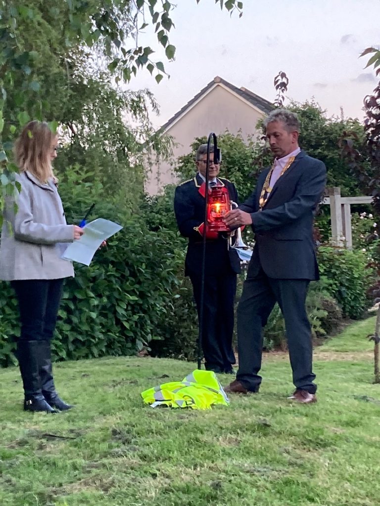 The Chair of Dodington Parish Council lights the lamplight whilst the Parish Clerk looks on